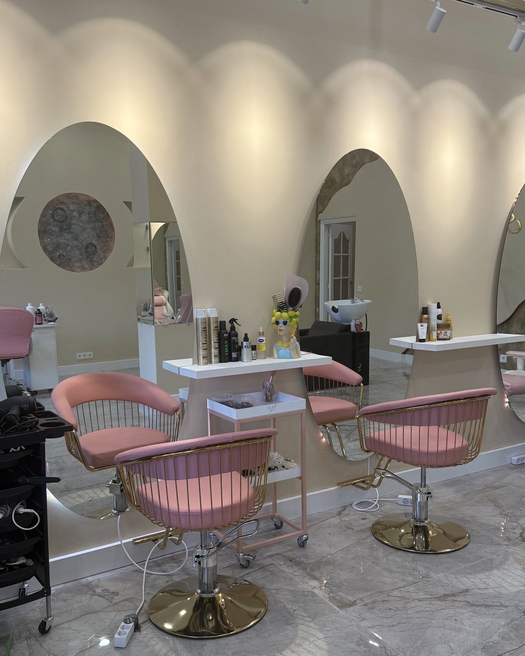 De salon met boogspiegels, roze stoelen en een marmeren vloer