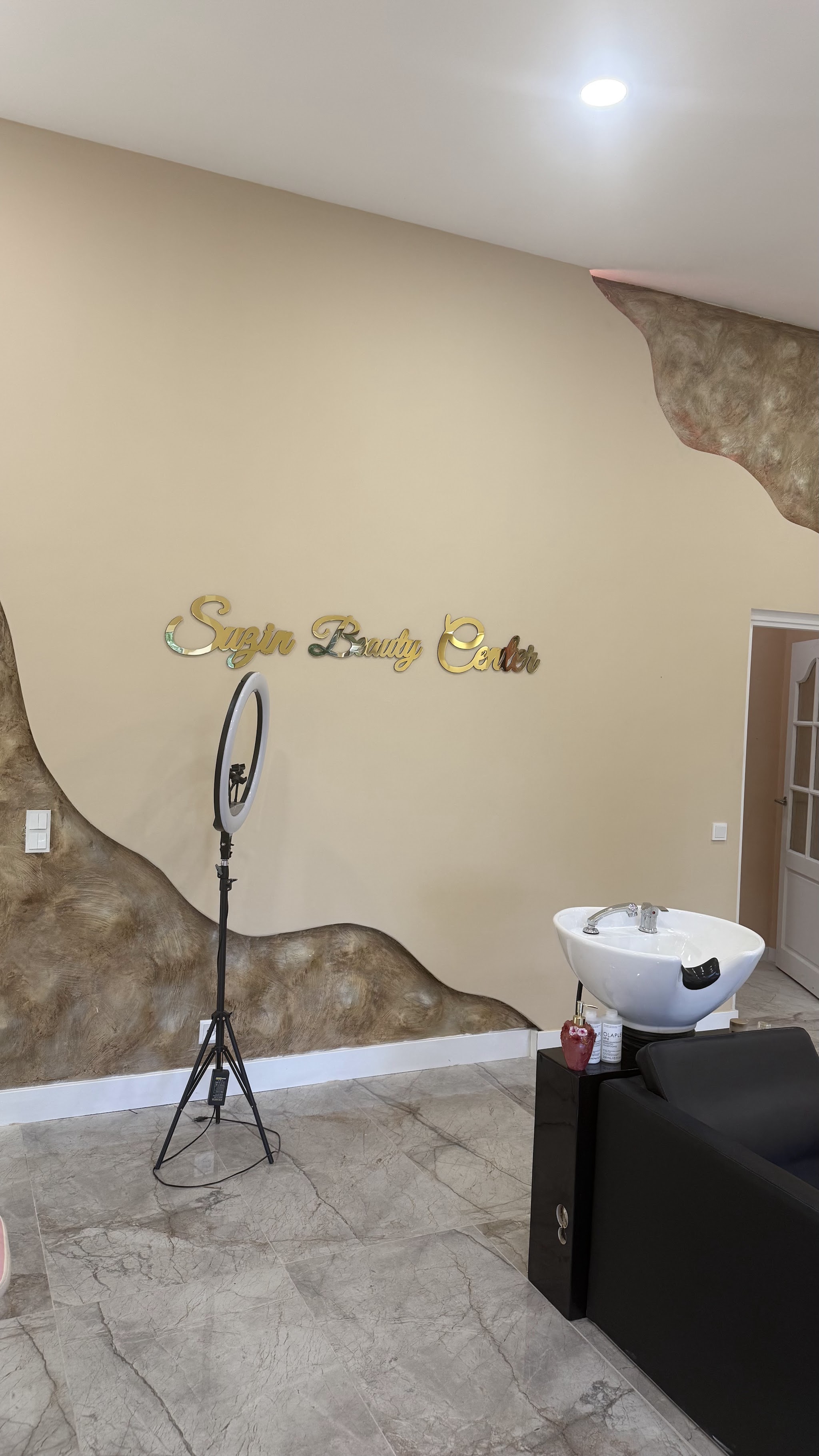 De wasplek voor de gouden golf op de muur, met de naam Suzin Beauty Center in gouden letters
